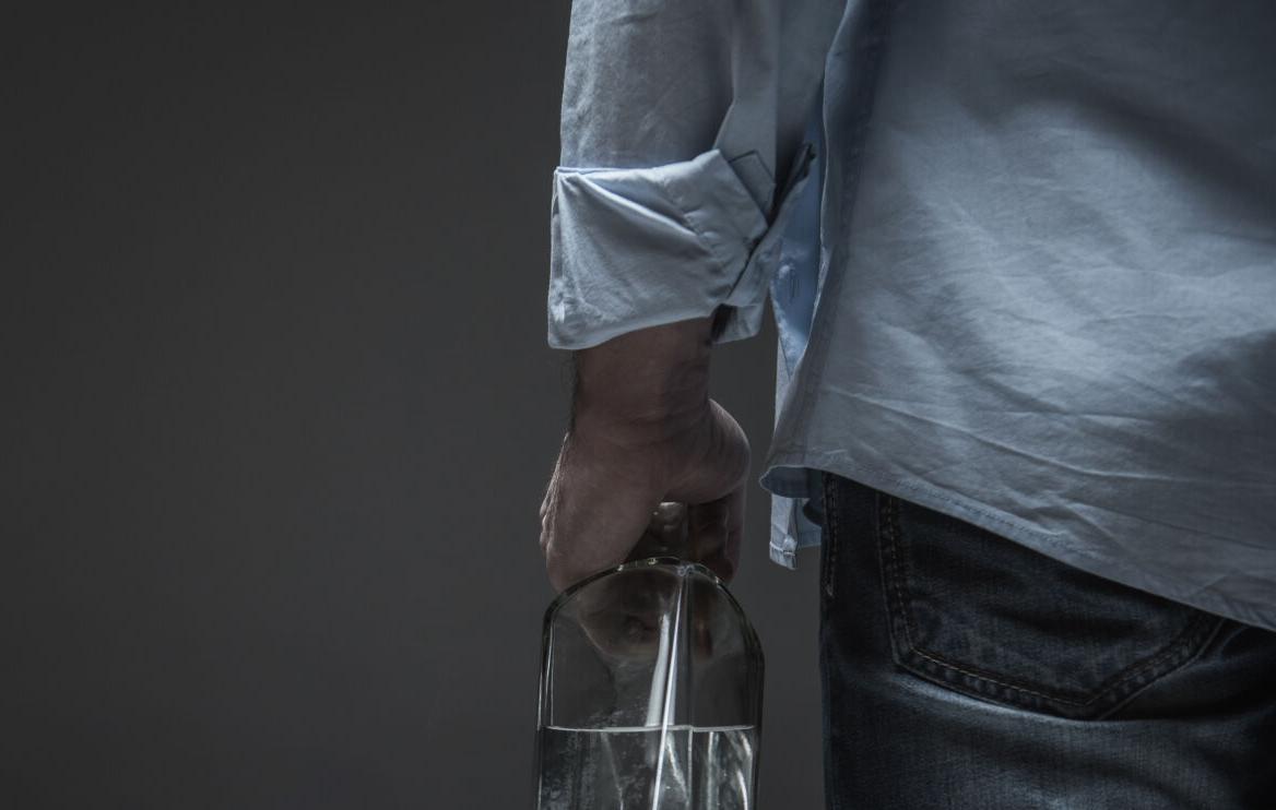 Photo of male back holding bottle in hand